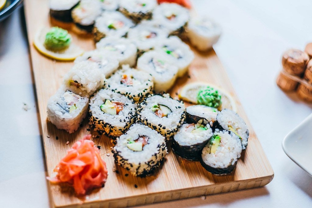 Et udvalg af smukt anrettede maki-ruller på et træbræt, som viser den restaurantkvalitet, man kan opnå med en måltidskasse derhjemme.